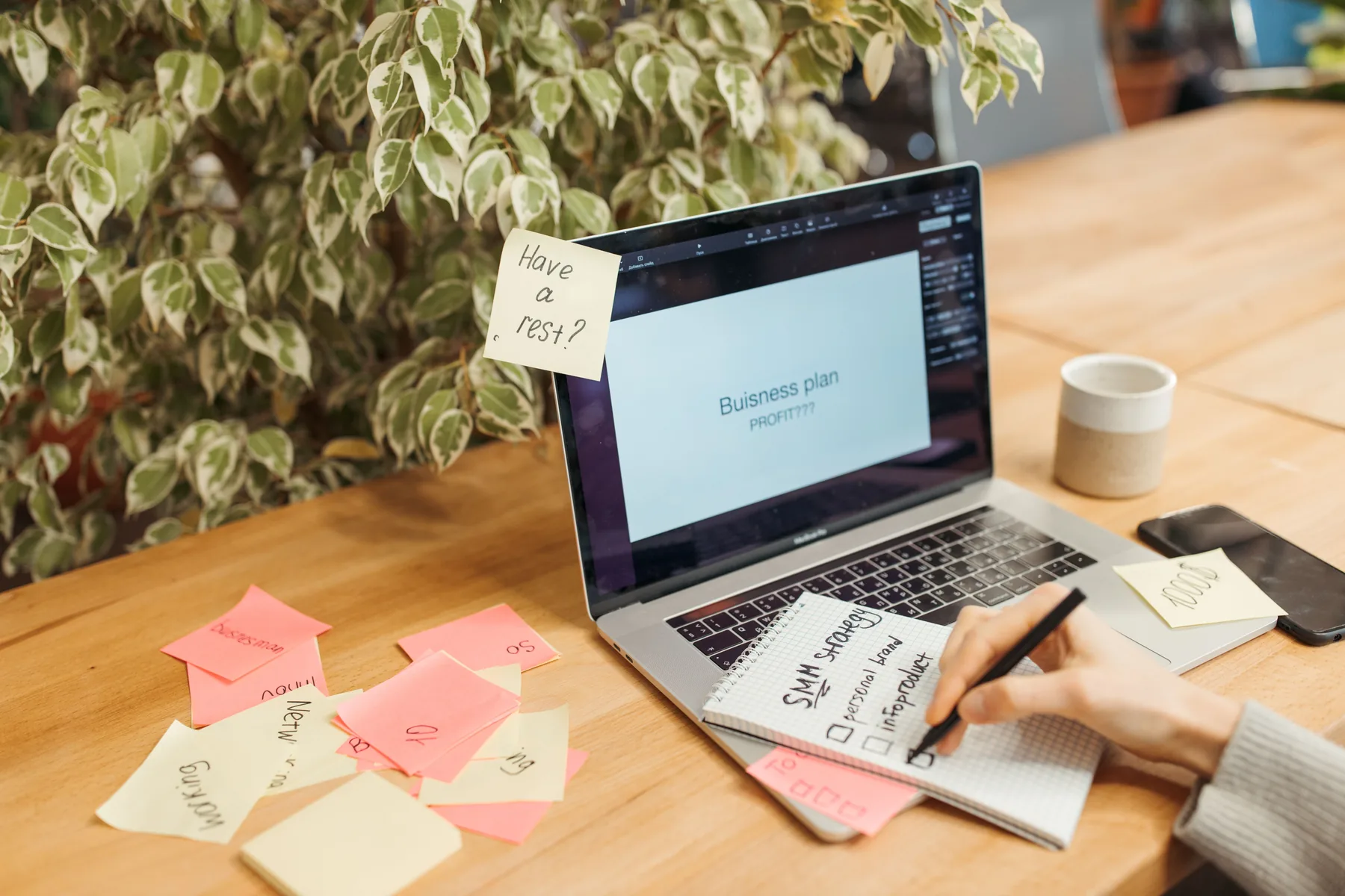 Laptop surrounded by planning notes during digital product planning